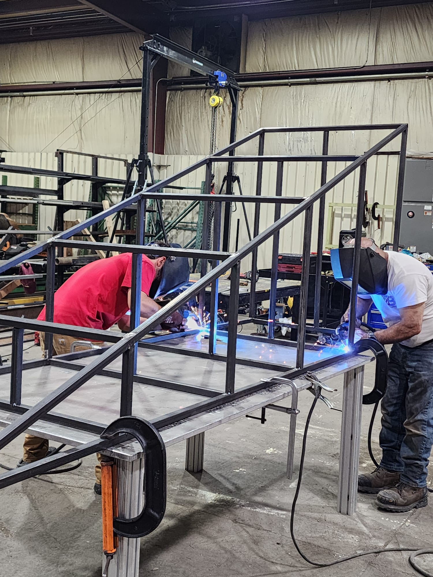 Two fabricators welding a steel frame in the iFab shop