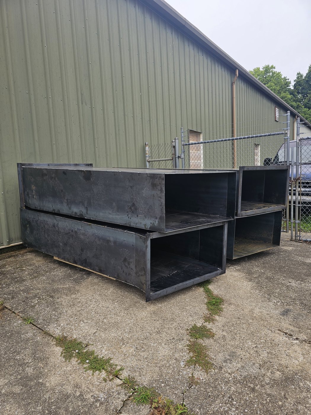 Unpainted steel hoppers staged outside the shop