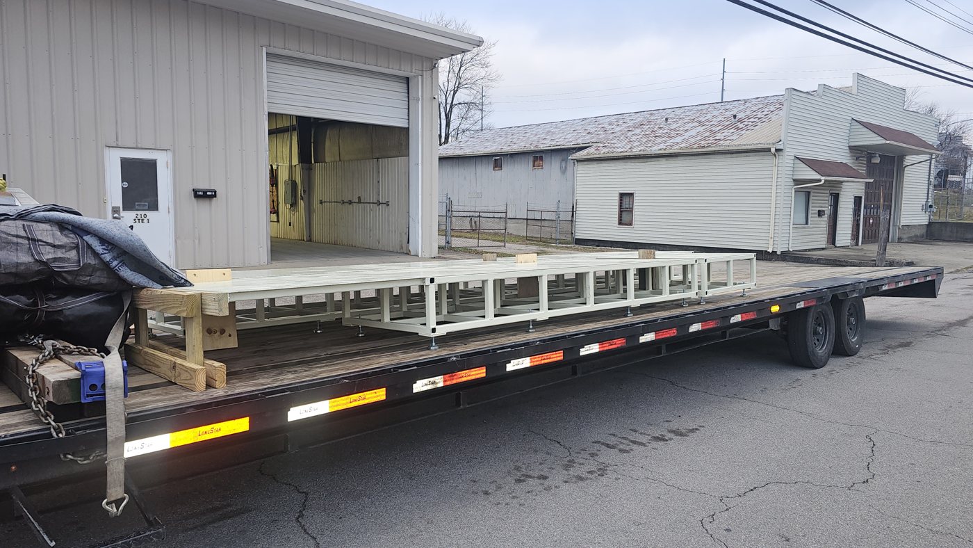 Heavy duty machine platform loaded on a flatbed trailer for delivery